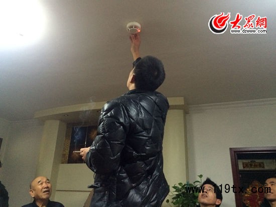 在居民家中試裝自動煙感報警器后，工作人員點燃一根香煙，報警器立刻亮起紅燈并發出警報