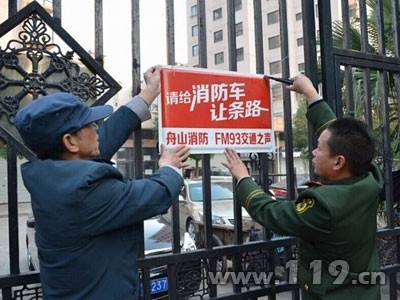 消防官兵和物業人員一起懸掛提示牌