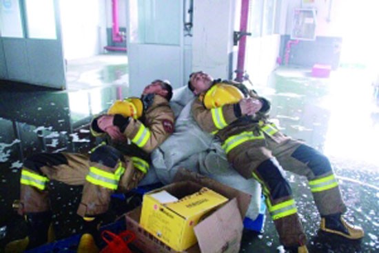 地面上都是水，消防戰士躺在沙袋上休息